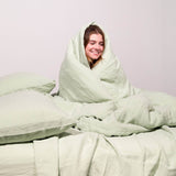 Girl wrapped in seafoam linen duvet with 2 seafoam linen pillows
