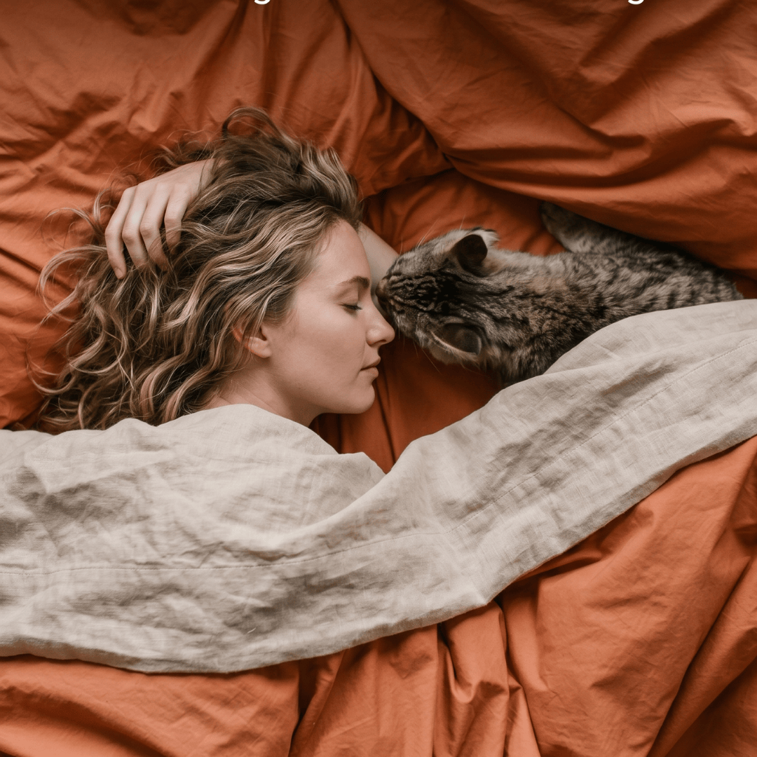 Woman lying in bed with a cat on an orange blanket