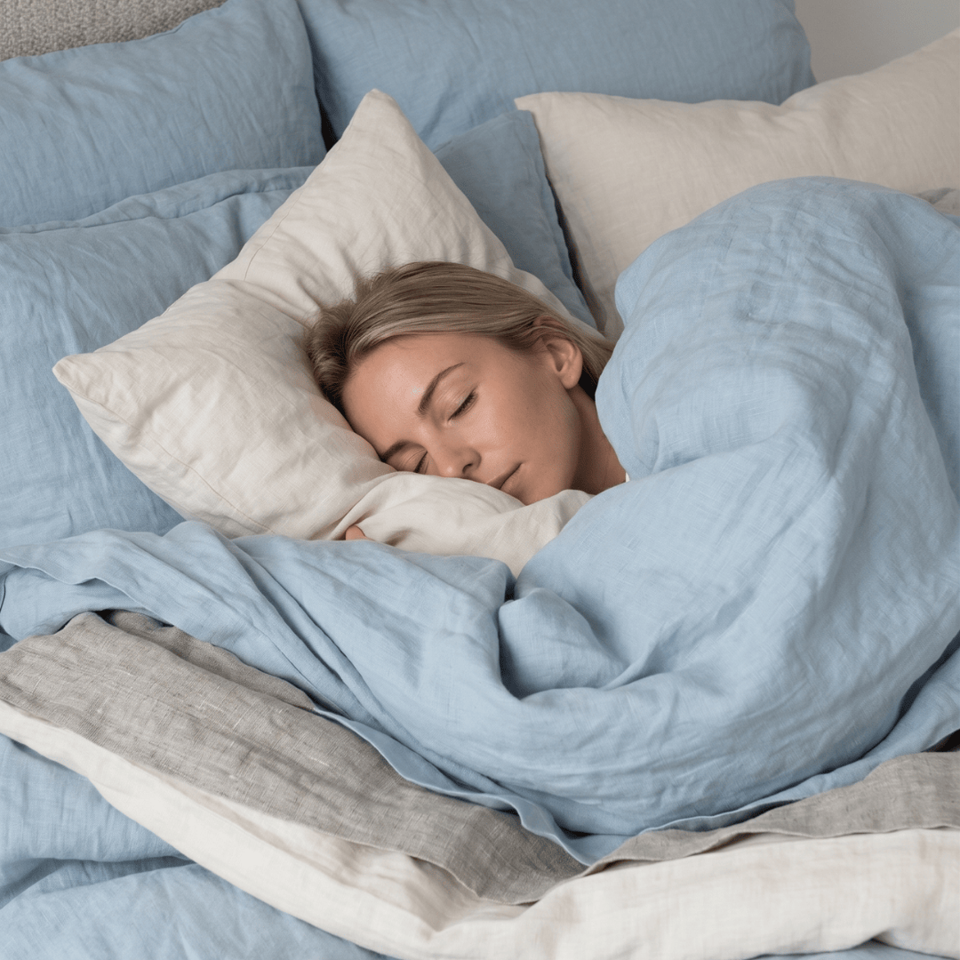 Woman sleeping under light blue bedding in a cozy bedroom setting
