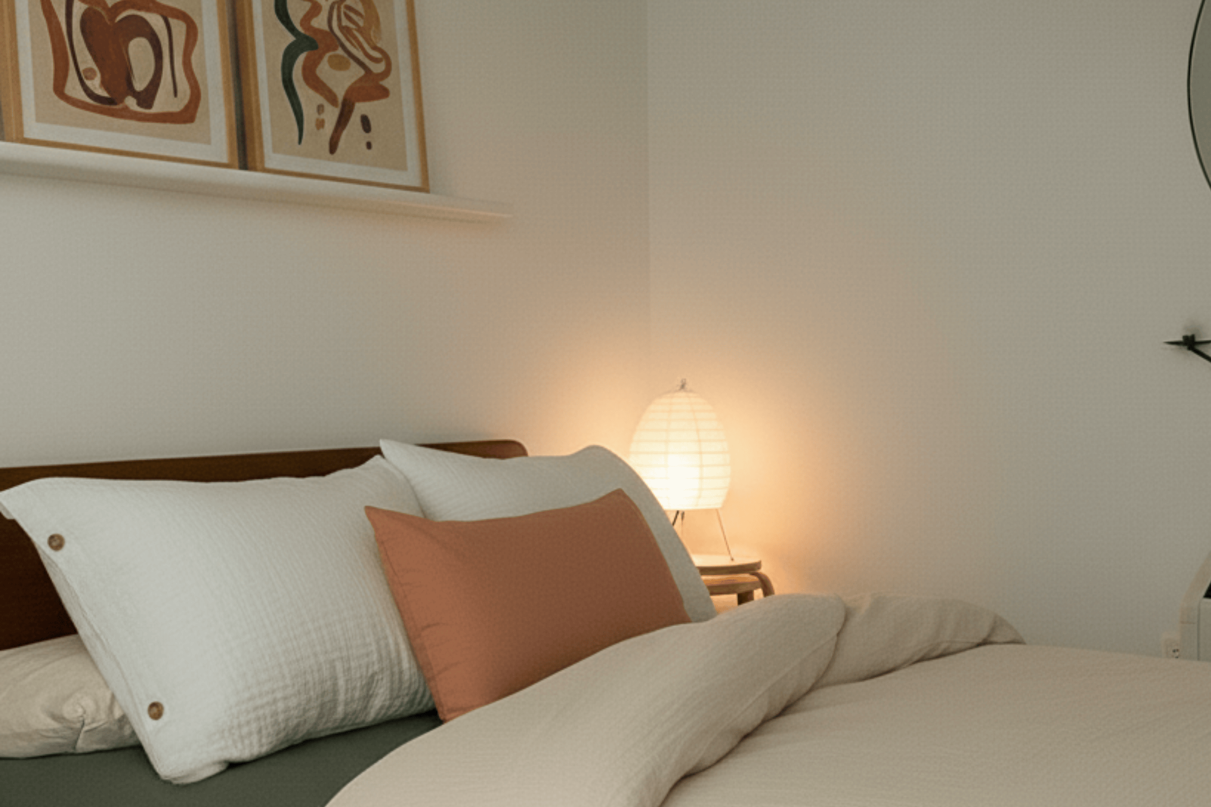 Bedroom with a bed featuring pillows and a lamp on a nightstand.