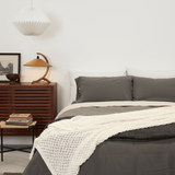 Bedroom with a bed featuring gray bedding and a wooden side table.