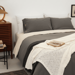 Bedroom with a bed featuring gray bedding and a wooden nightstand.