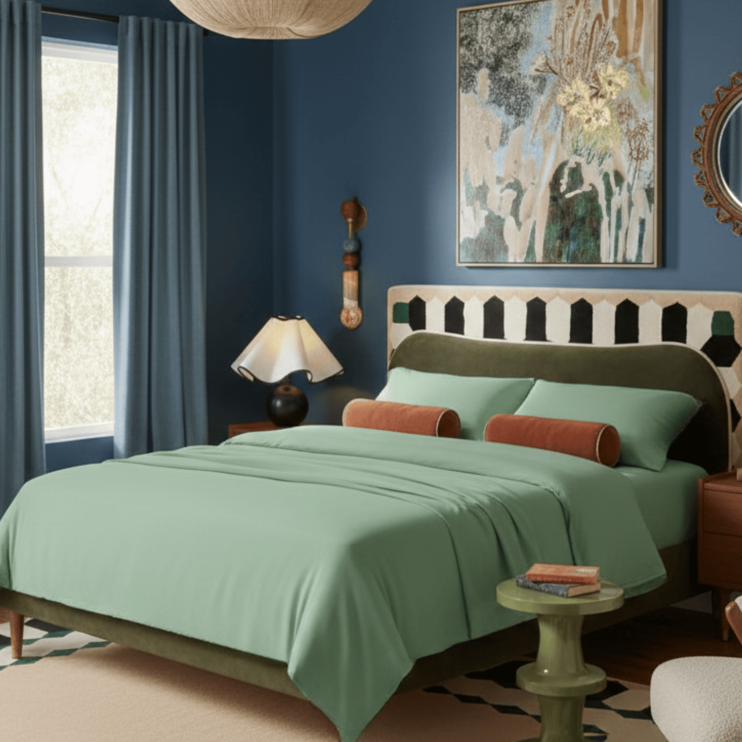 Cozy bedroom with green bedding, decorative pillows, and a stylish lamp.