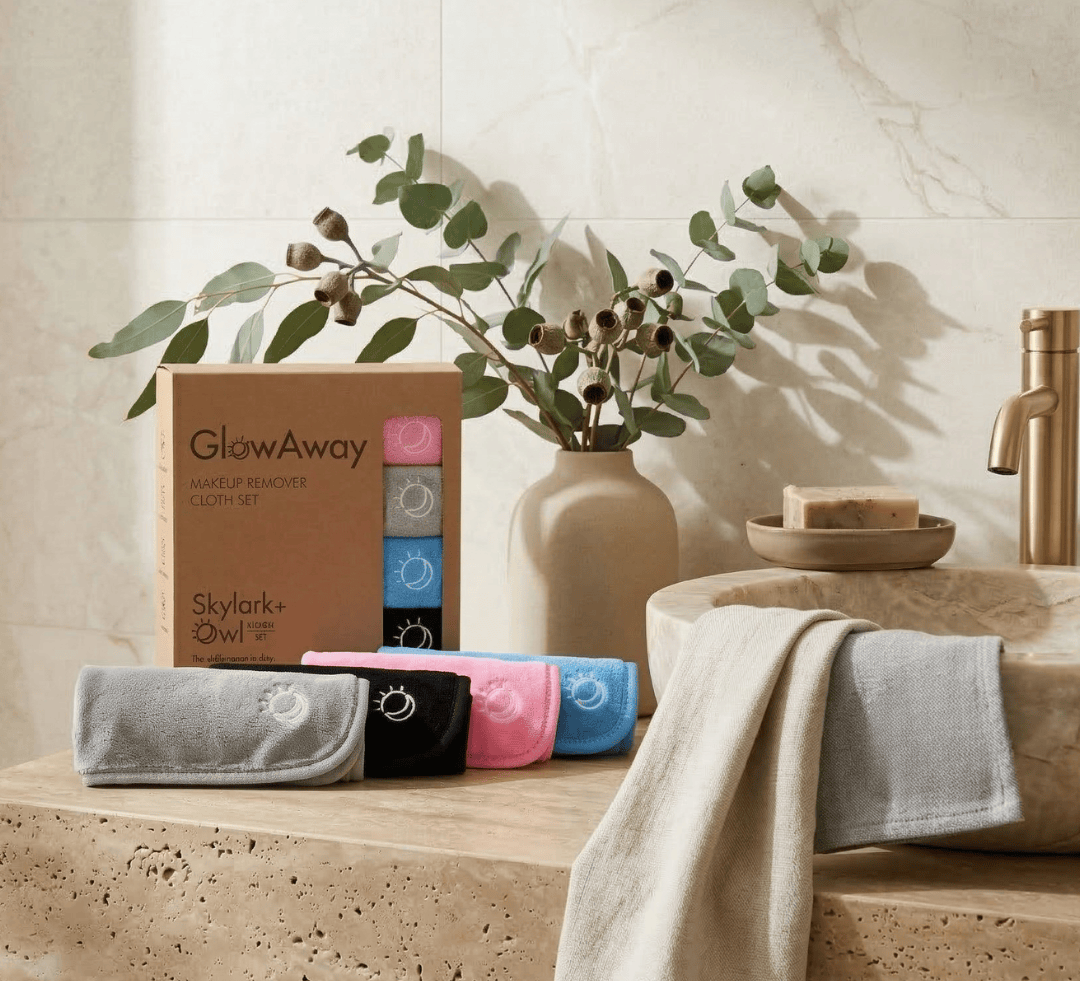 Bathroom setting with towels, a plant, and a box labeled 'GlowAway' on a marble countertop.