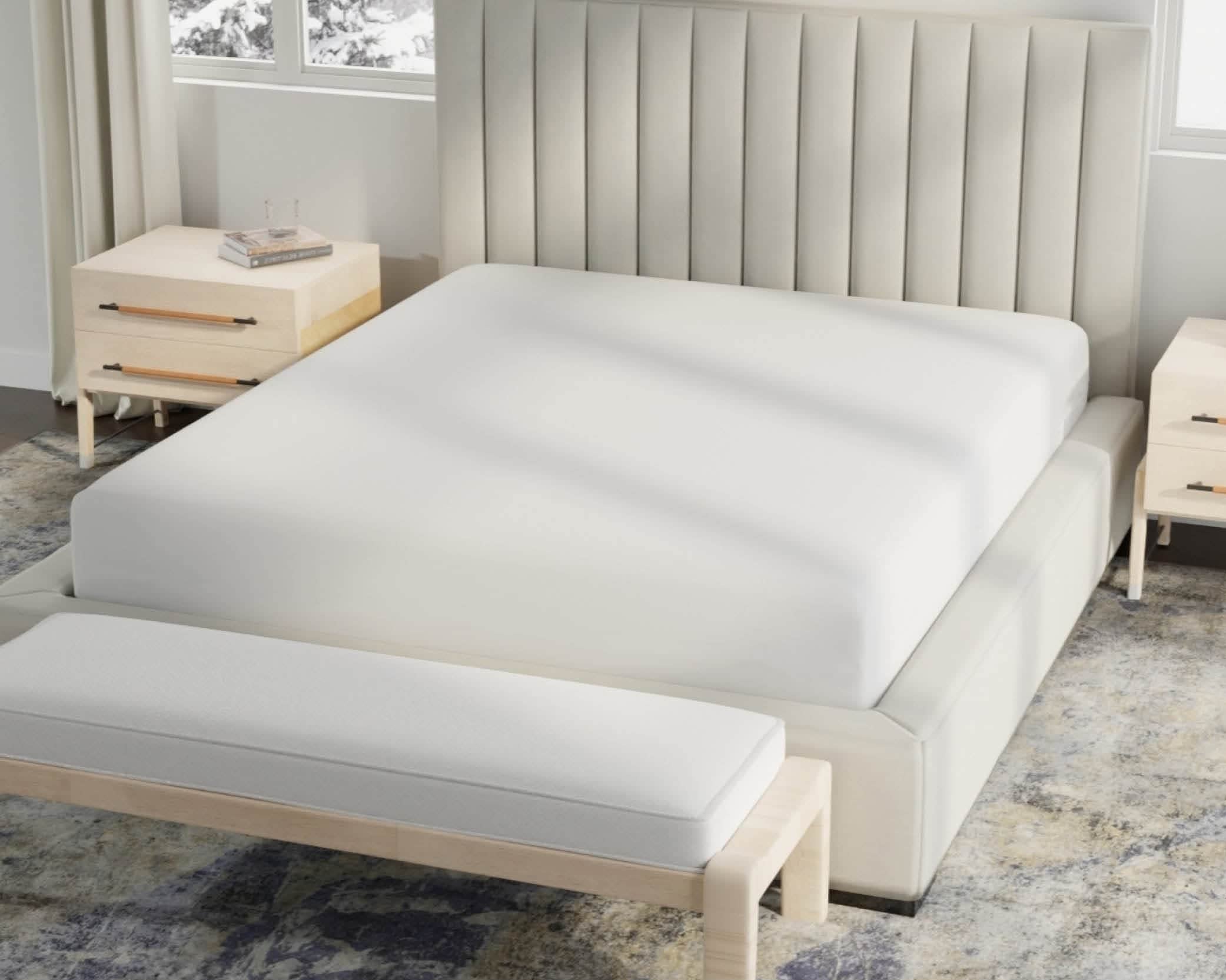 Image of a bed in a neutral colored room with just a white Cooling 5-Sided Mattress Protector on the bed