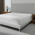 Image of a mattress protector on a bed with a gray headboard