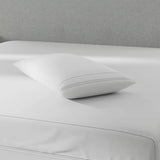 Image of a pillow protector on top of a gray bed with just a mattress protector on it