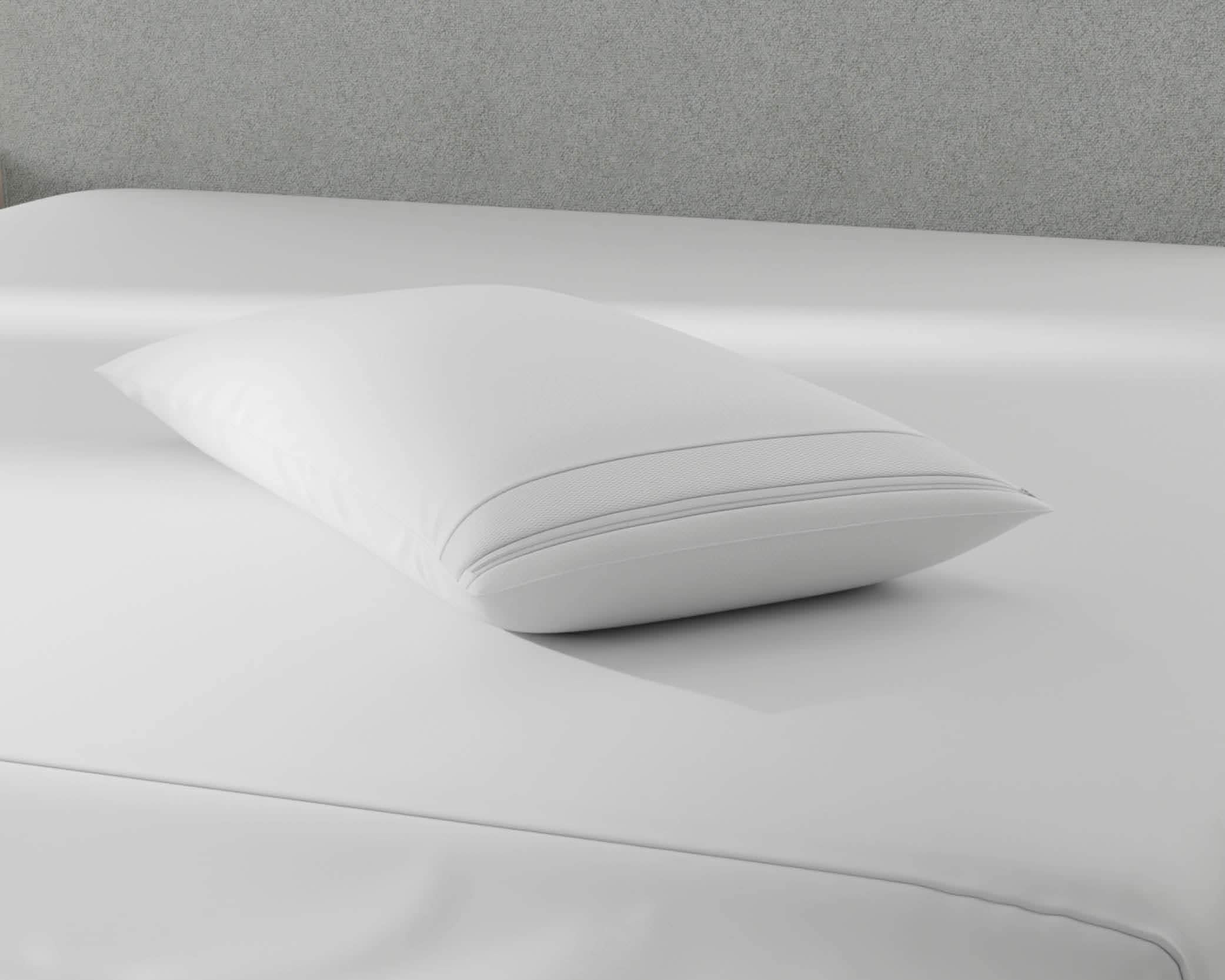 Image of a pillow protector on top of a gray bed with just a mattress protector on it