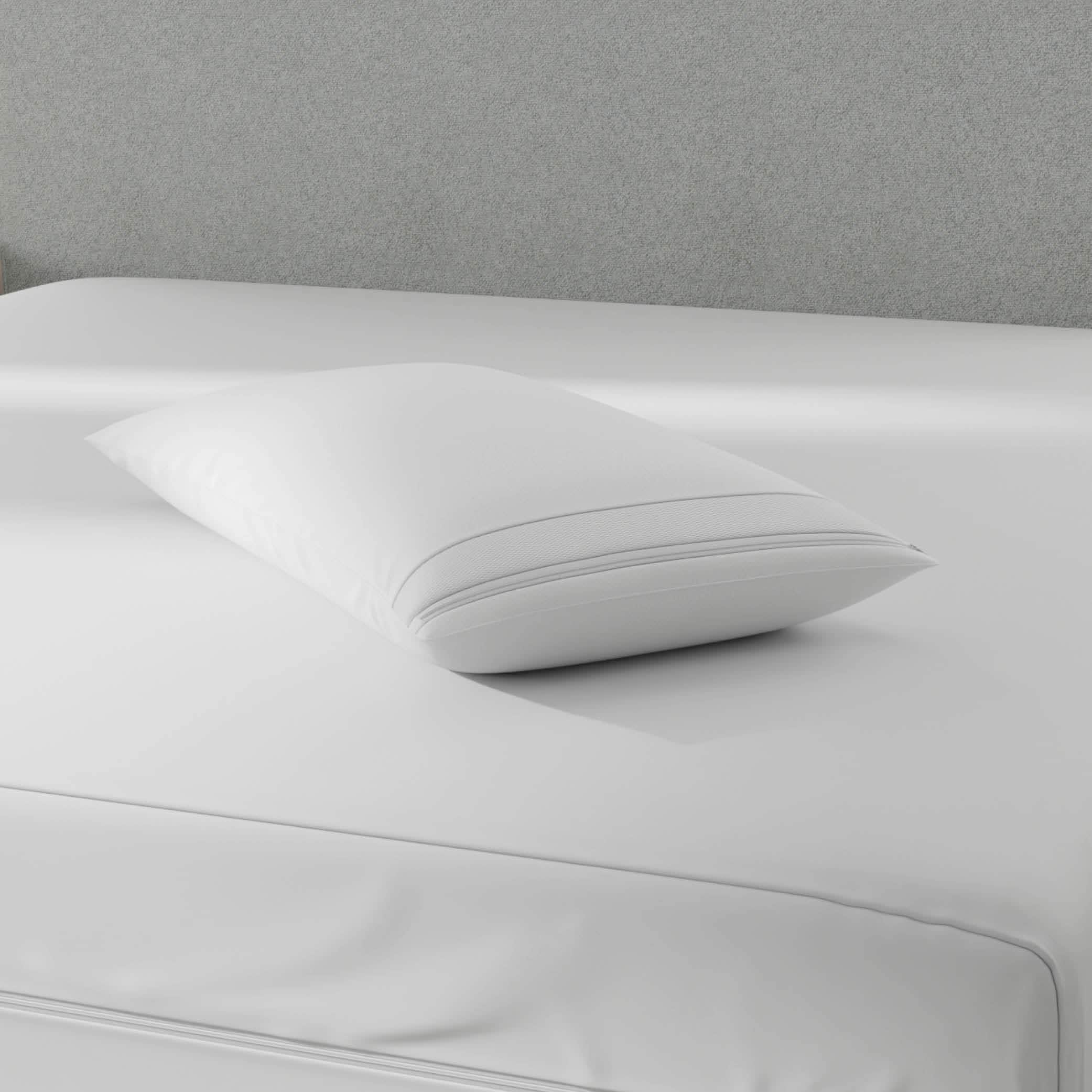Image of a pillow protector on top of a gray bed with just a mattress protector on it