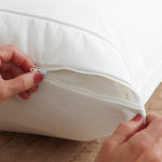 Image of two hands zipping a pillow protector closed