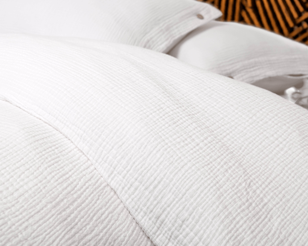 Close-up of crinkled white cotton gauze duvet cover and pillows