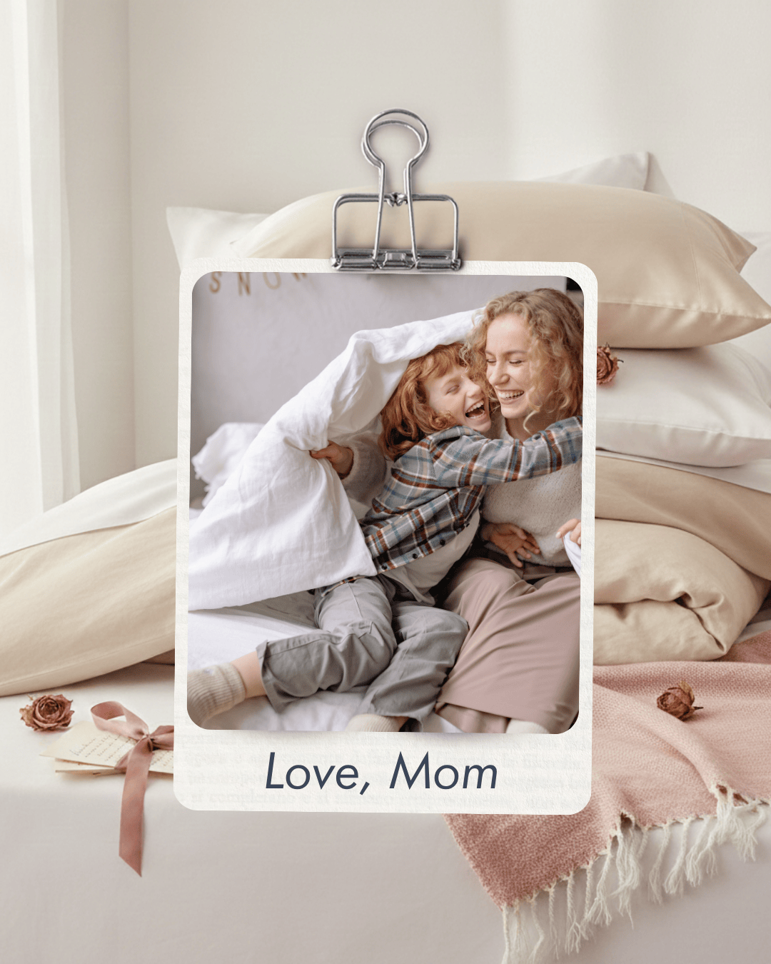 Two children hugging under a blanket with 'Love, Mom' text overlay on a bed.