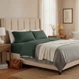 Neatly made bed with green and gray bedding in a bedroom setting.