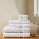 Stack of white towels on a wooden surface with a mirror in the background.