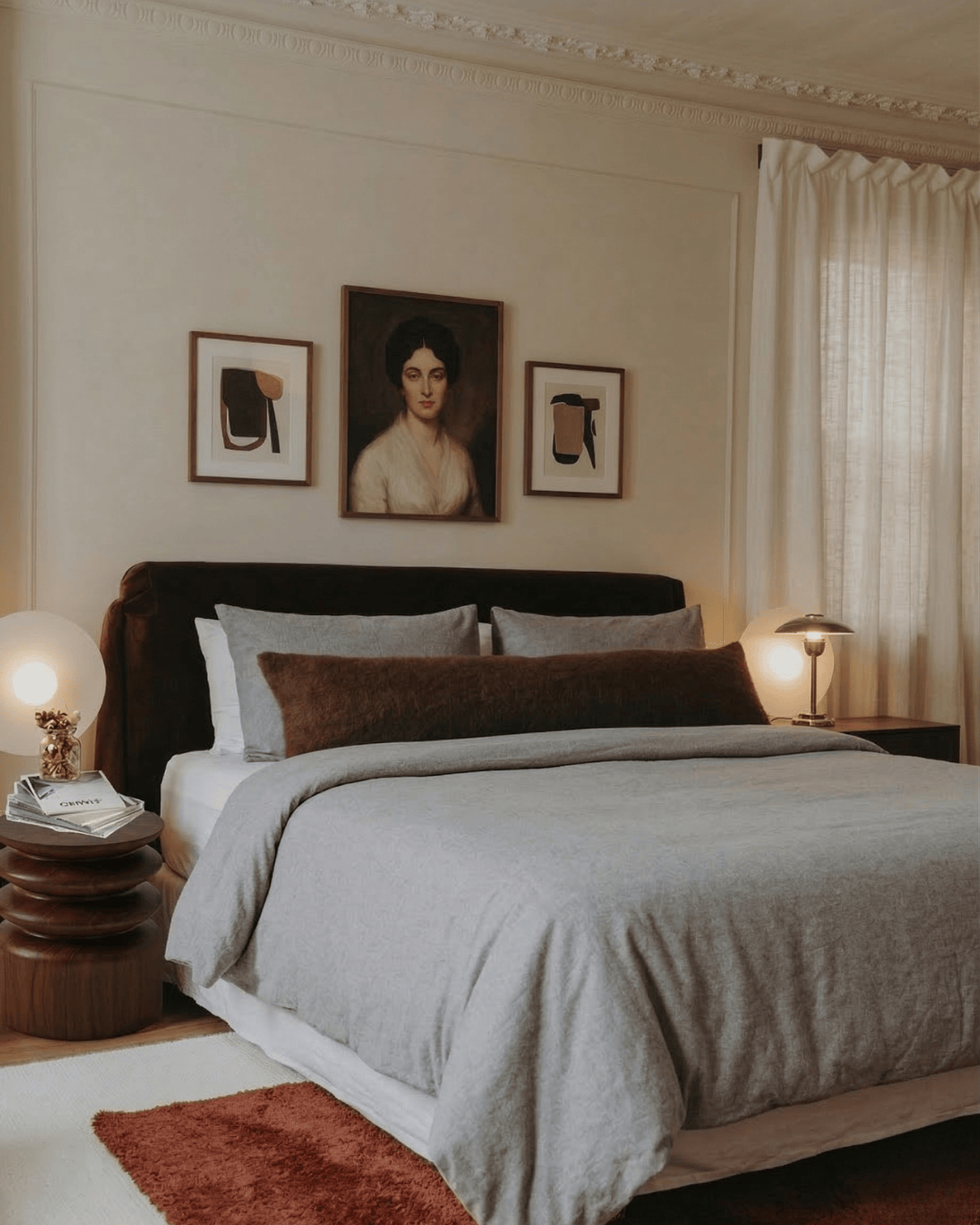 Neatly made bed in a bedroom with decorative pillows and wall art.