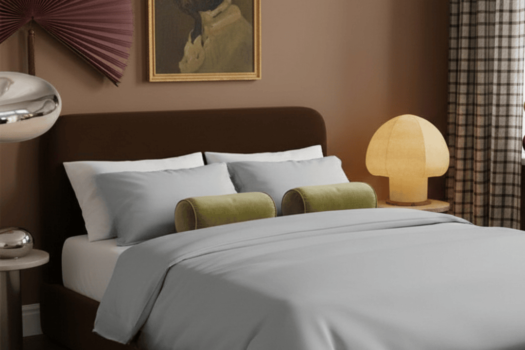 Modern bedroom with a bed, lamp, and decorative items on a brown wall.