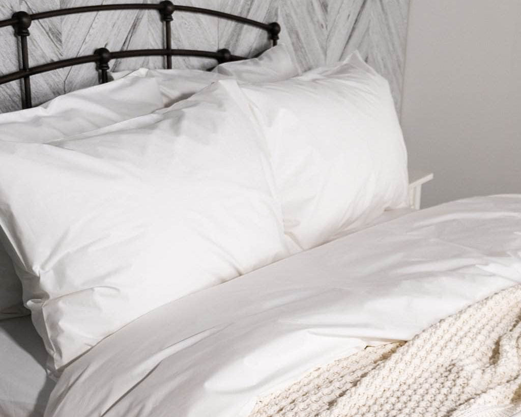 White organic percale bedding on a bed with a black metal headboard