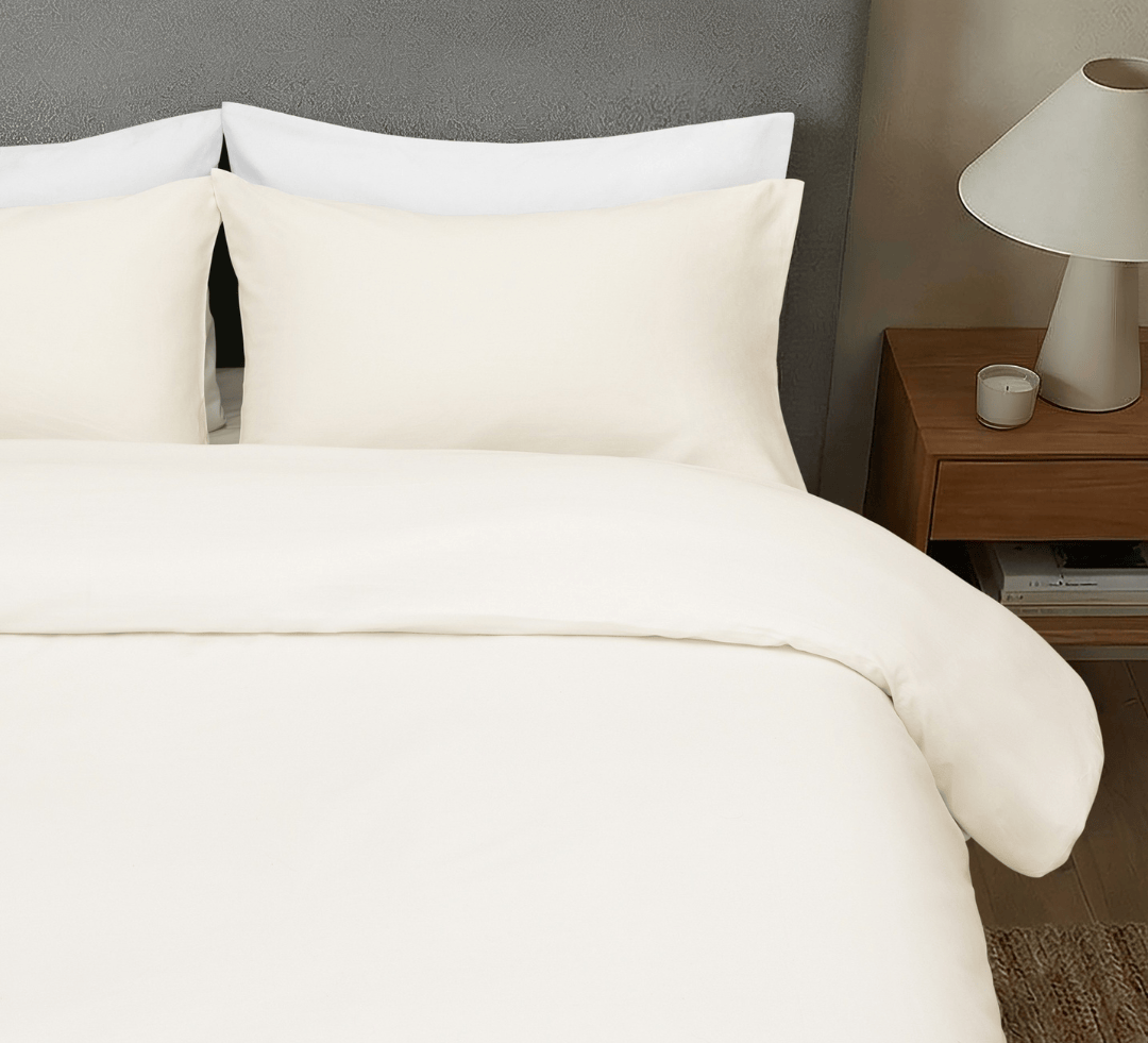 Neatly made bed with chalk bedding and pillows in a bedroom setting.