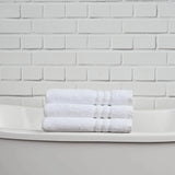 Stack of white towels on a white surface with a white brick wall background