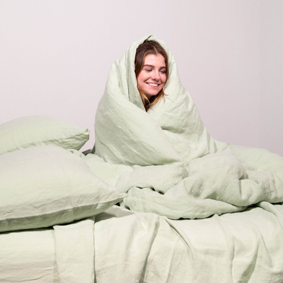 Girl wrapped in seafoam linen duvet with 2 seafoam linen pillows 