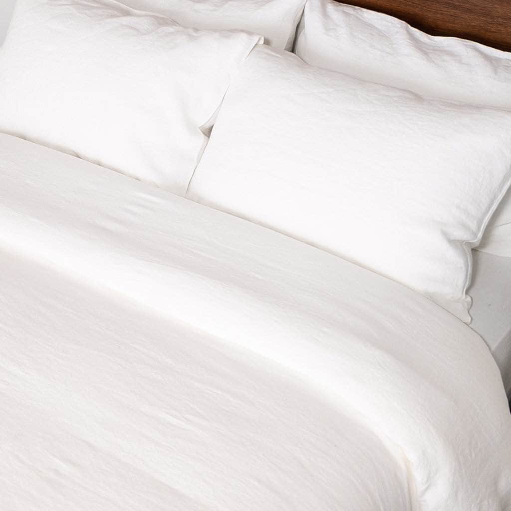 close up of bed with white linen duvet and white linen sheet set