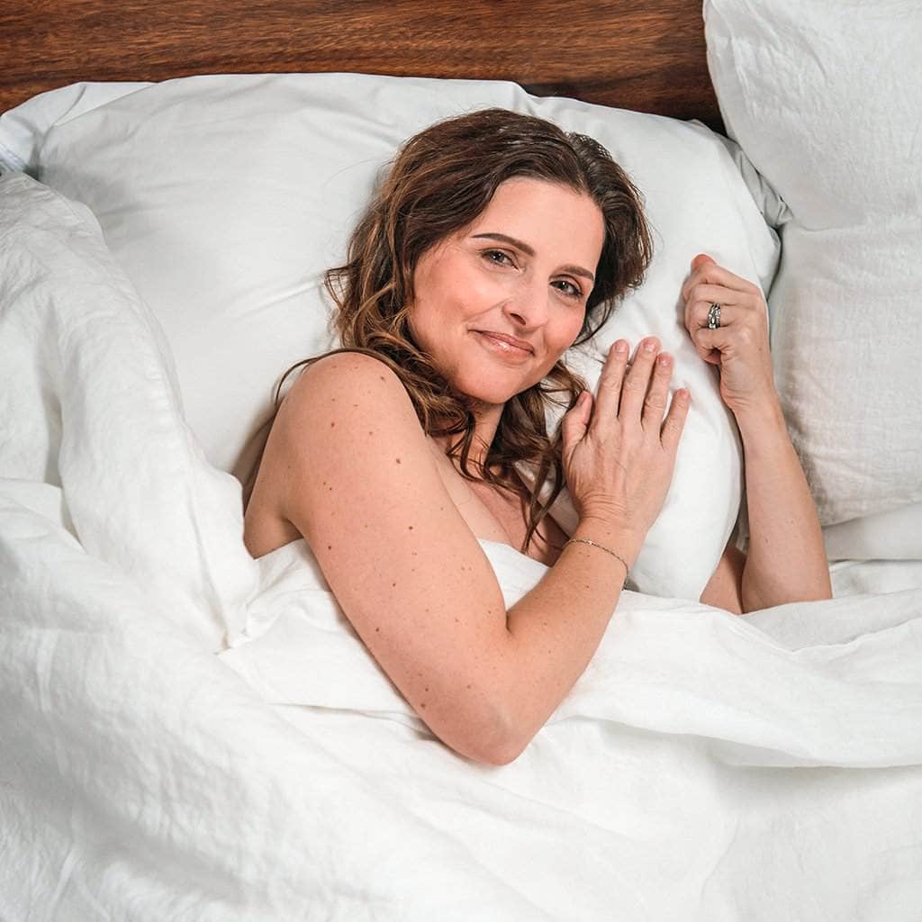 Woman laying in bed featuring Linen Duvet Cover in White