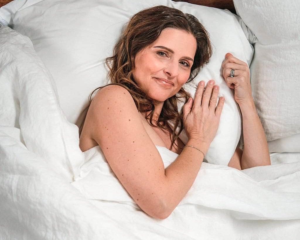Woman laying in bed featuring Linen Duvet Cover in White