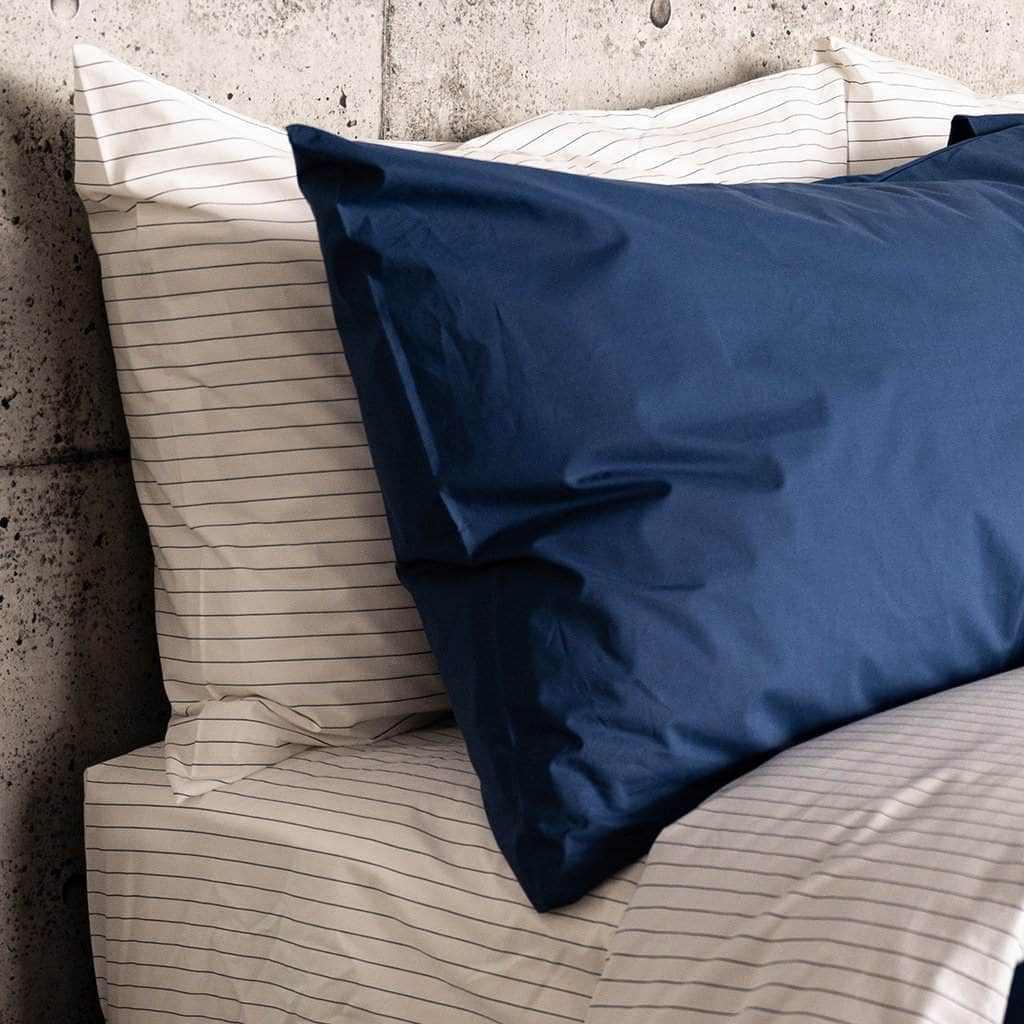 Bed featuring the Essential Collection Percale Pillowcases in Charcoal Stripe and in Navy