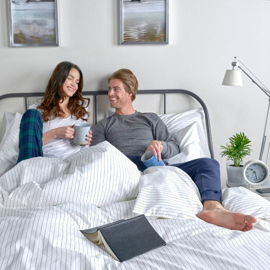 Couple relaxing in bed featuring the Essential Collection Percale Sheet Set in Charcoal Stripe