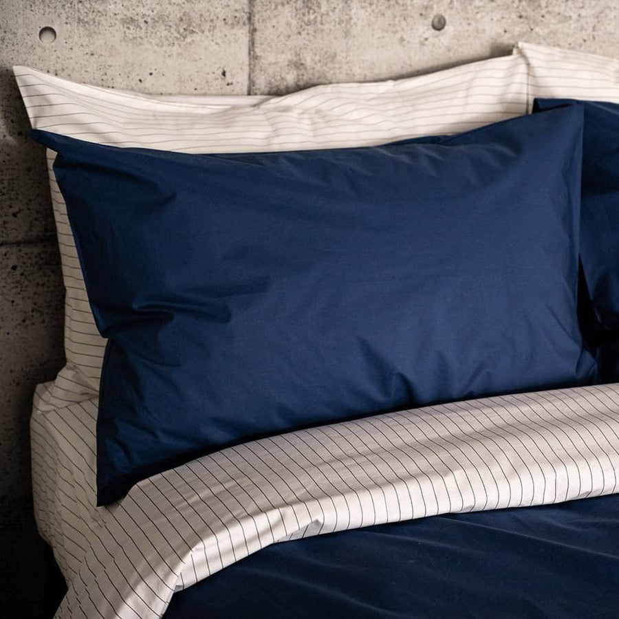 Close up of bed with Essential Collection Percale Sheet Set in Navy and Charcoal Stripe