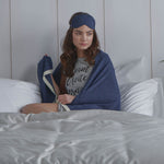 Woman in bed wrapped with Blanket in Navy and wearing an Eye Mask in the same colour